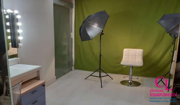 zona de fotografia con cromas verde, una silla para el paciente y dos paraguas de luz de fotografia, espejo tocador para los pacientes